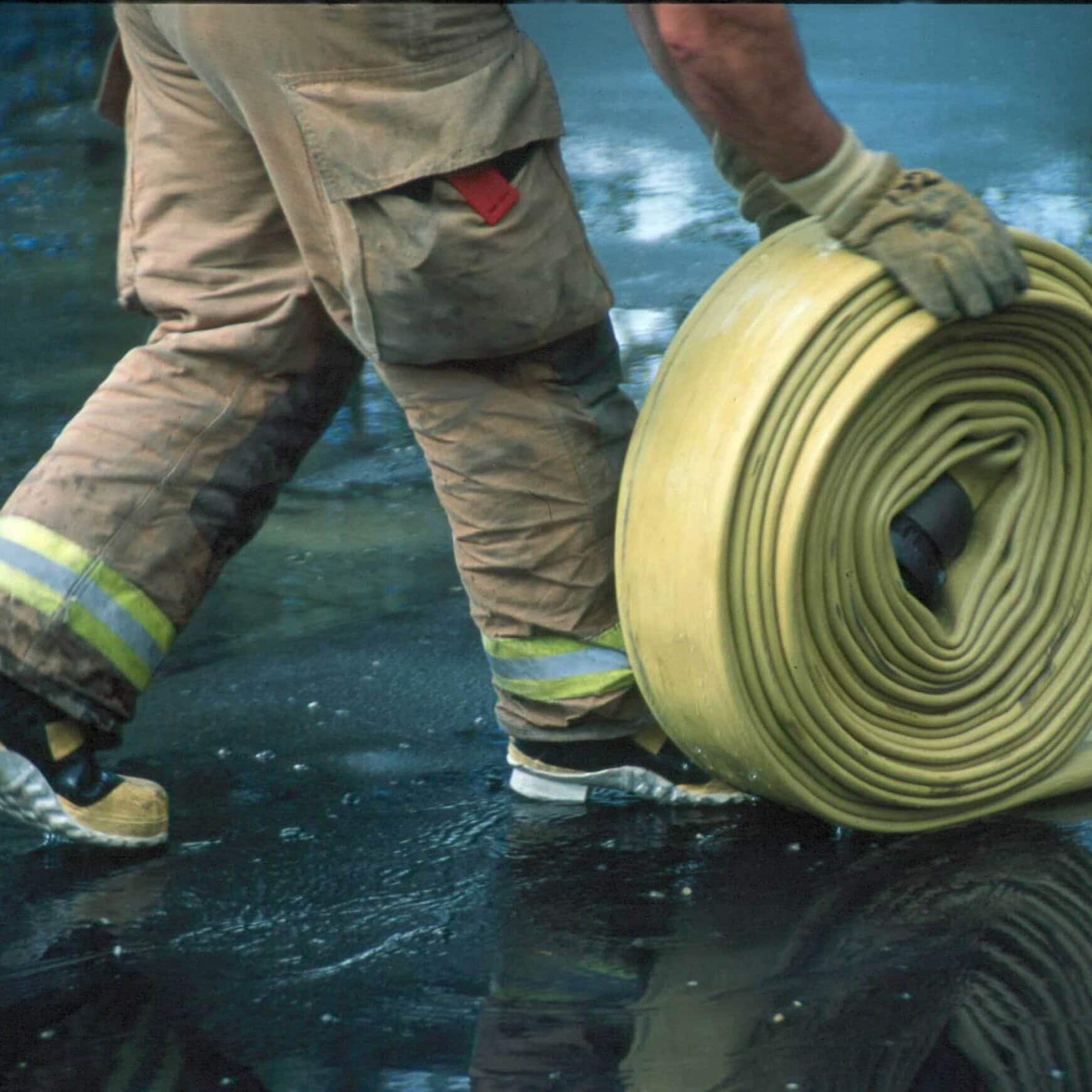 Firefighter rolling up hose