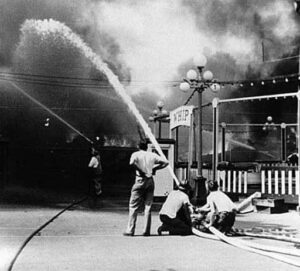 Historical photo of Firefighters spraying fire hose