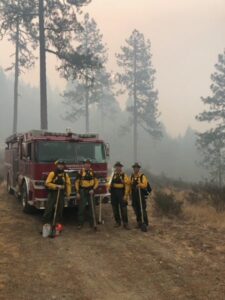 Four Firefighters posing in wildfire smoke
